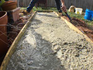 Concrete being worked while fiber strands are pulled up through the mix